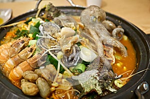 Hot Korean seafood stew with various ingredients including small octopus, shrimps, abalones, trumpet shells, warty sea squirts, a