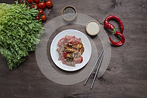 Hot Korean-style eggplant and tomato salad with sesame seeds and herbs. Asian food. Vegetarian dish. Wood background. Place for