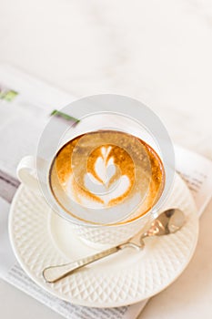 hot latte art coffee with newspaper on wooden table, vintage and