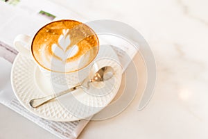 hot latte art coffee with newspaper on wooden table, vintage and