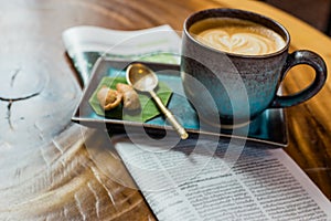 hot latte art coffee with newspaper on wooden table, vintage and