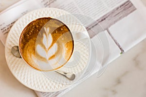 hot latte art coffee with newspaper on wooden table, vintage and