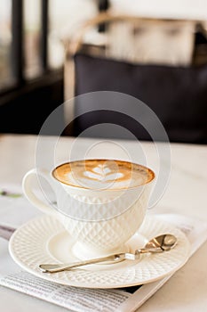 hot latte art coffee with newspaper on wooden table, vintage and