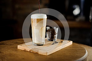 Hot latte coffee in a high glass cup on a wooden board