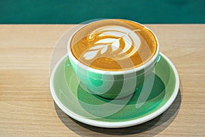 Hot latte coffee with leaf art latte shape on green mug