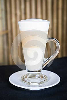 Hot latte coffee on a wood table with a bamboo background