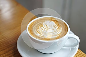 Hot Latte - A cup of coffee with milk and beautiful leaf pattern latte art on wooden table and copy space, Perfect for breakfast