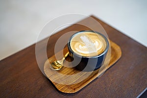 Hot Latte - A cup of coffee with milk and beautiful leaf pattern latte art on wooden table and copy space, Perfect for breakfast