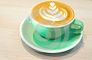 Hot latte with leaf art latte shape in green mug