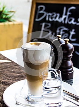 Hot latte macchiato coffee with tasty foam and cinnamon