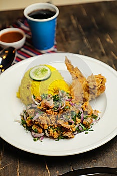 Hot Lemony Chicken Rice Meal served in plate with sauce, cold drink, spoon and fork isolated on wooden board side view of thai