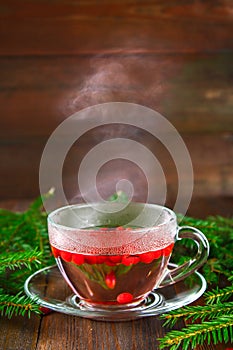hot lingonberry, cranberry, foxberry, cowberry tea in glass cup, rustic background.