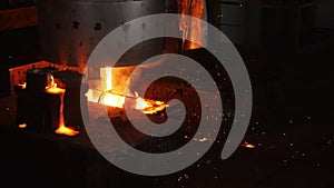 Hot liquid metal poured into form and sparks fly in workshop