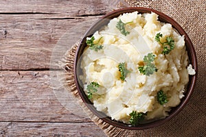Hot mashed potatoes with parsley in a bowl close-up. top view photo