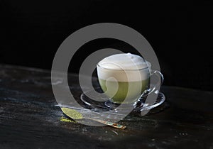 Hot Matcha green tea latte in a cupon a dark background. Fashionable energy tea photo