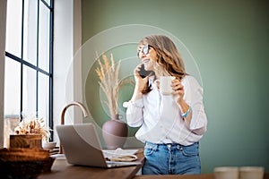 Hot of middle aged woman using mobile phone and laptop while working from home