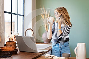 Hot of middle aged woman using mobile phone and laptop while working from home