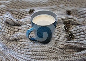Hot milk drink in a blue mug and a warm scarf