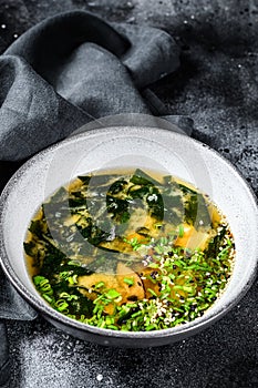Hot miso soup in a bowl. Black background. Top view