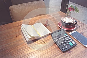 Hot mocha coffee, calculator and smart phone with working book on the wooden table
