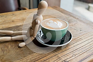 Hot mocha coffee or capuchino in the green cup lean by wood man on the wooden table