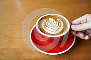 Hot Mocha - Holding a cup of coffee with milk, cocoa and beautiful latte art on wooden  table and copy space.