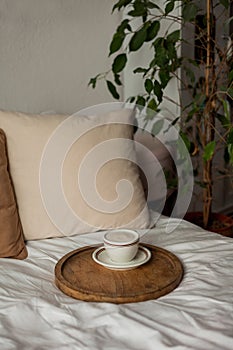 Hot mug of cappuccino on wooden tray on the bed, breakfast. Cozy house. Beige natural colors. Aesthetic