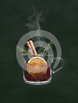 Hot mug of christmas mulled wine with orange, cinnamon and spices, on a black background