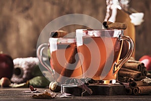 Hot mulled apple cider with with cinnamon sticks, cloves and anise on wooden background. Traditional autumn, winter drinks and