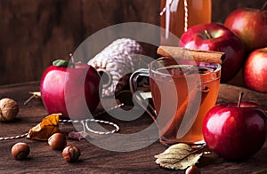 Hot mulled apple cider with with cinnamon sticks, cloves and anise on wooden background. Traditional autumn, winter drinks and