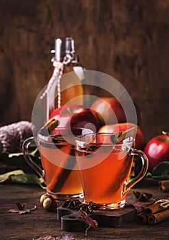 Hot mulled apple cider with with cinnamon sticks, cloves and anise on wooden background. Traditional autumn, winter drinks and