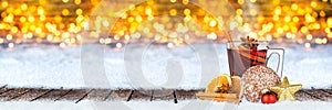 Hot mulled spiced red wine in glass mug with gingerbread orange