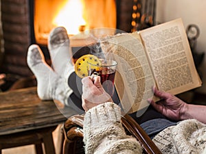 Hot mulled wine and book in woman hands. Relaxing in front of bu