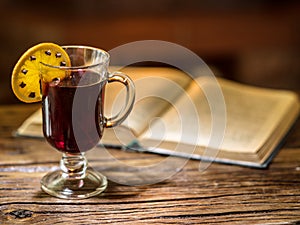 Hot mulled wine and a book on the wooden table