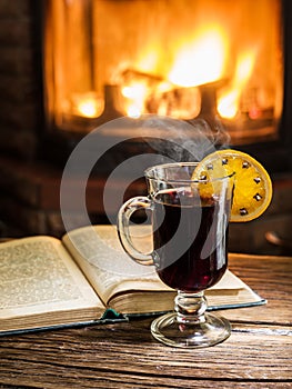 Hot mulled wine and a book on the wooden table.