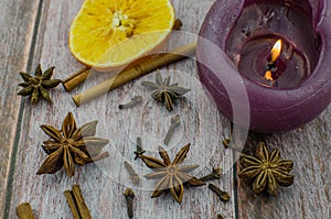 Hot mulled wine drink with lemon, apple, cinnamon, anise and other spices in a glass cup between fir tree branches on wooden