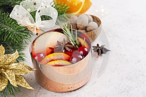 Hot mulled wine with fruits and spices in a copper pot