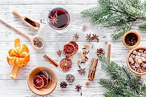 Hot mulled wine or grog cooking for new year celebration with oranges and spices ingredients on light background flat