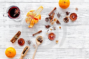 Hot mulled wine or grog cooking for new year celebration with oranges and spices ingredients on light background flat