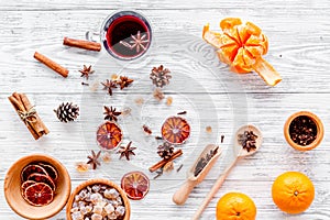 Hot mulled wine or grog cooking for new year celebration with oranges and spices ingredients on light background flat