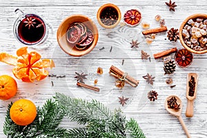 Hot mulled wine or grog cooking for new year celebration with oranges and spices ingredients on light background flat