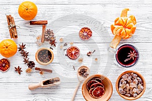 Hot mulled wine or grog cooking for new year celebration with oranges and spices ingredients on light background flat