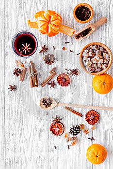 Hot mulled wine, grog cooking for new year celebration with oranges and spices ingredients on light background flat lay