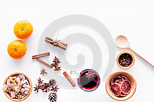 Hot mulled wine or grog cooking for new year celebration with oranges and spices ingredients on white background flat