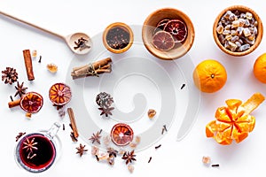 Hot mulled wine or grog cooking for new year celebration with oranges and spices ingredients on white background flat