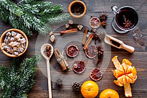 Hot mulled wine or grog cooking for new year celebration with oranges and spices ingredients on wooden background flat