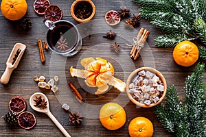 Hot mulled wine or grog cooking for new year celebration with oranges and spices ingredients on wooden background flat