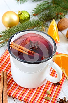 Hot mulled wine in a mug on a white wooden background. A traditional warming winter wine drink with aromatic spices