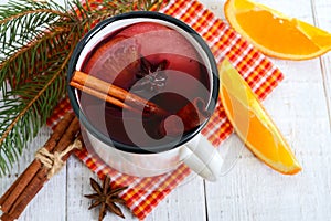 Hot mulled wine in a mug on a white wooden background. A traditional warming winter wine drink with aromatic spices