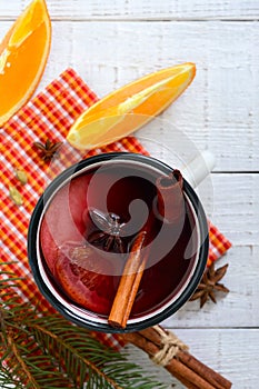 Hot mulled wine in a mug on a white wooden background. A traditional warming winter wine drink with aromatic spices